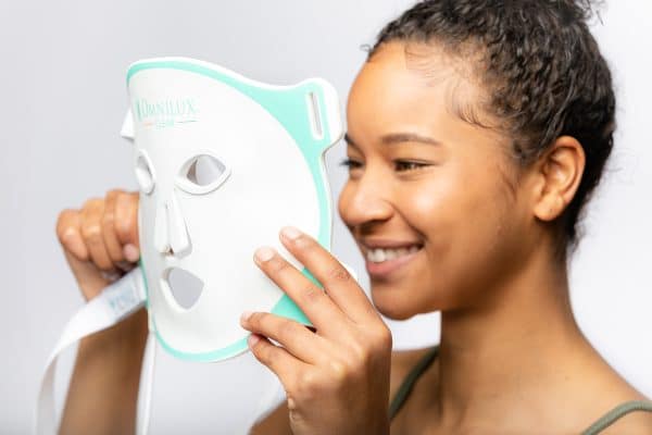 Omnilux Clear being put on face by woman